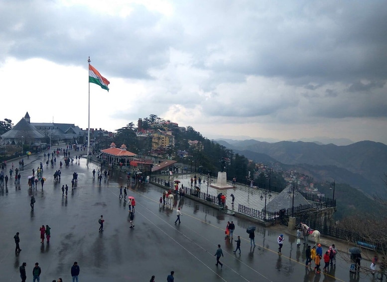 A wet square with a flag, buildings, and a mountain backdrop. 4