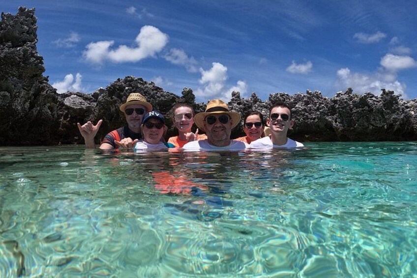 A group of people in clear water with a rocky background. 5