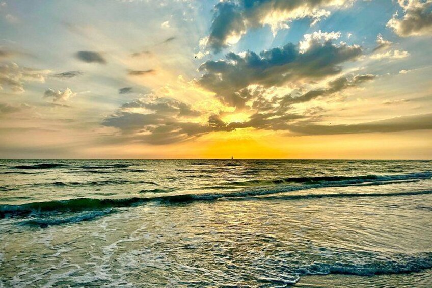 A sunset over the ocean with waves and a cloudy sky. 2