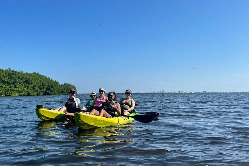 A group of people kayaking on a calm lake with a city skyline in the background. 1