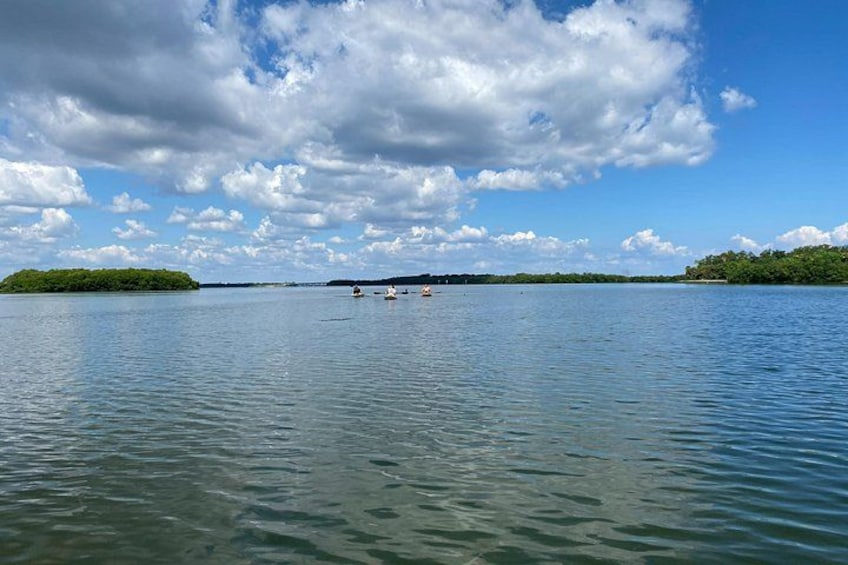A calm lake with boats, a clear sky, and distant land. 4