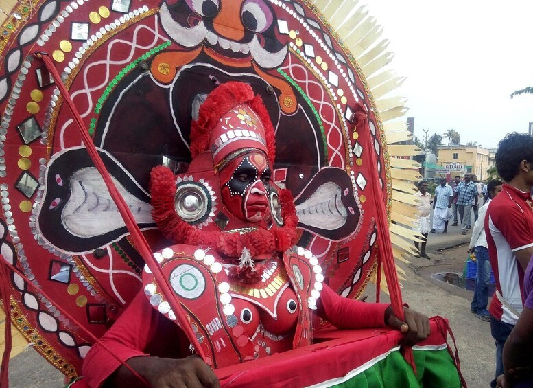 A person in a red and green costume with a large decorative headpiece. 4