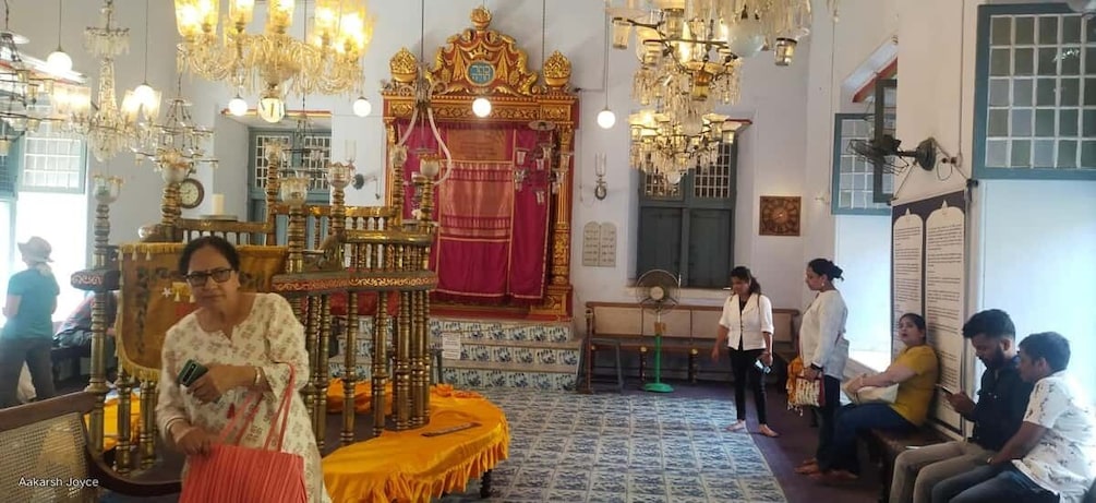 A traditional temple interior with ornate chandeliers, a golden altar, and a red curtain. 3