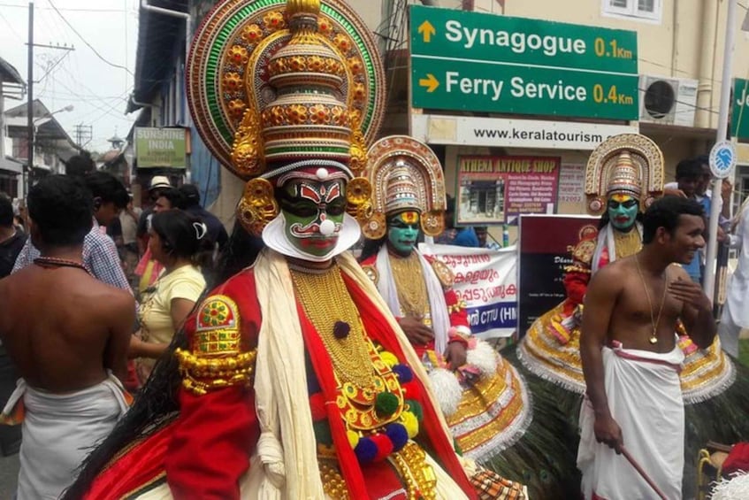 A group of people in traditional Indian attire, including elaborate headdresses and costumes, walking down a street. 1