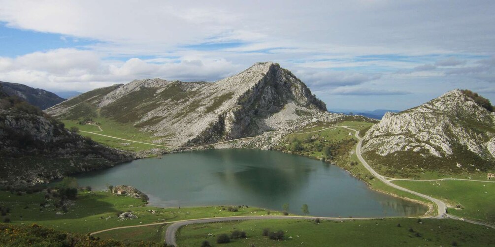 A lake surrounded by mountains, a winding road, and a small building. 1