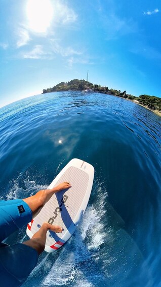 A person surfing on a wave with a clear view of a coastal landscape in the background. 1