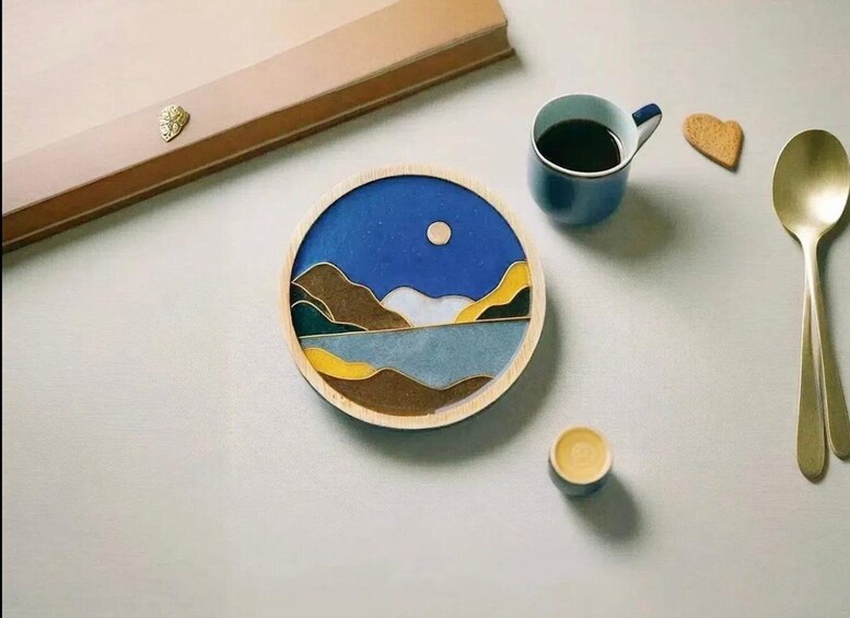 A wooden bowl with a painted landscape, a blue mug, a spoon, a heart-shaped cookie, and a small container. 4