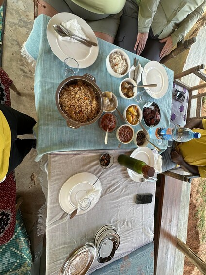 A table with various dishes, including rice, beans, and a large pot of food, set outdoors. 5