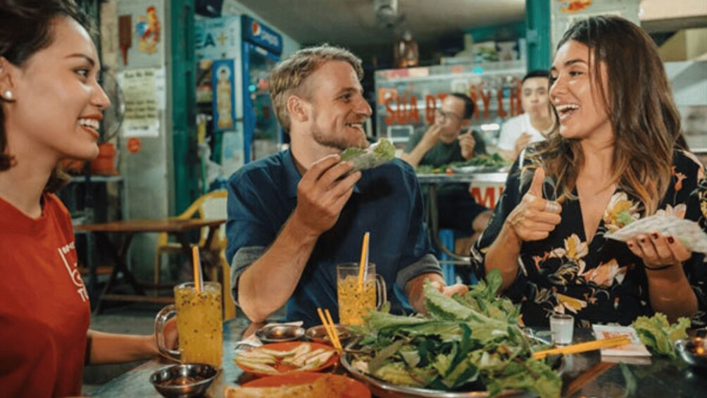 A group of people dining at a restaurant with various dishes and drinks on the table. 2