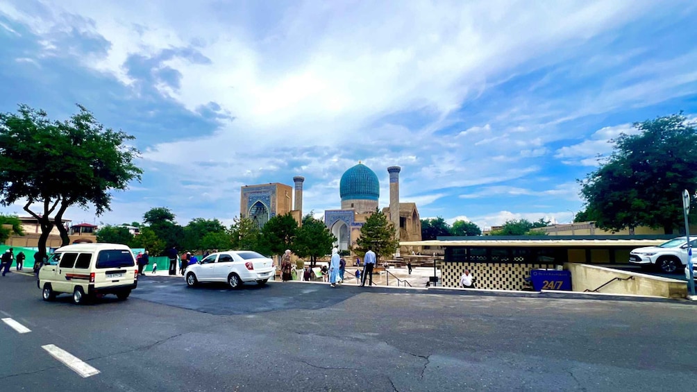 A street with cars, a bus, and a large mosque with a blue dome. 2