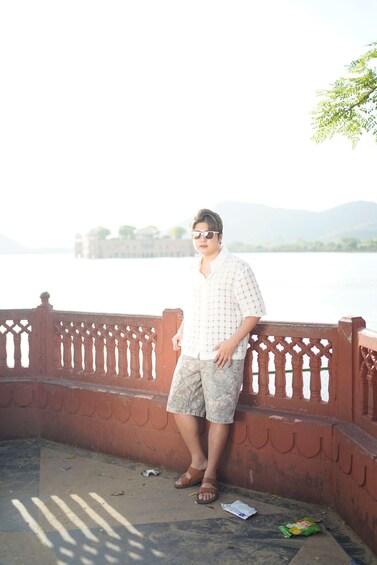A person standing on a bridge with a river and mountains in the background. 4