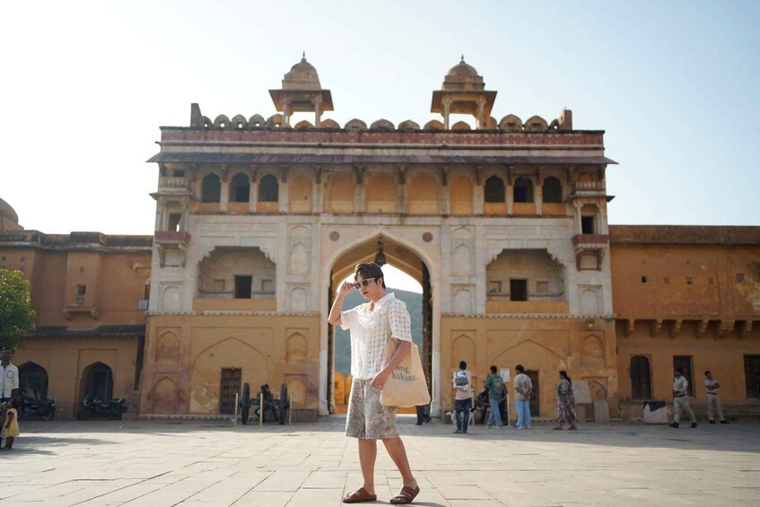 A person standing in front of a historic gate with arches and domes. 3