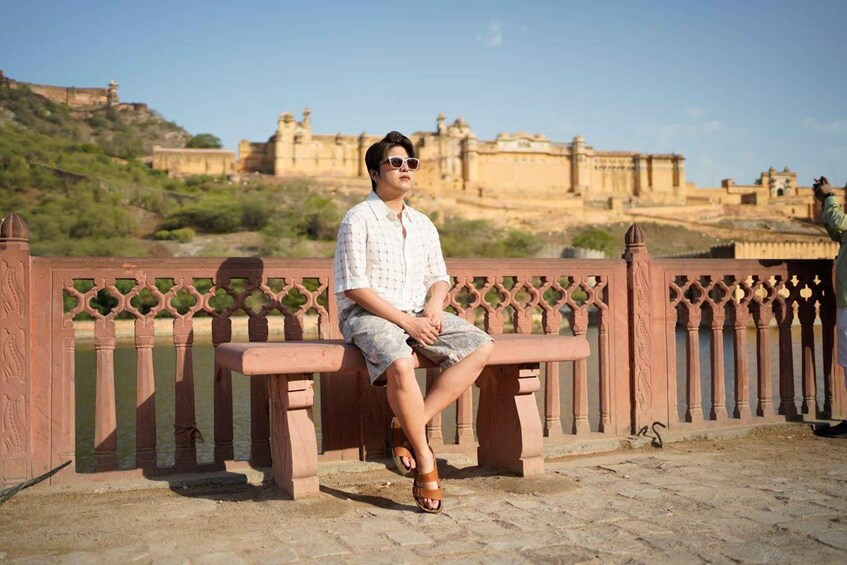 A person sitting on a bench with a historical fort in the background. 2