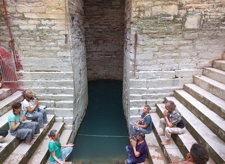 A group of people sitting on stone steps in a narrow passageway with a water channel in the center. 1