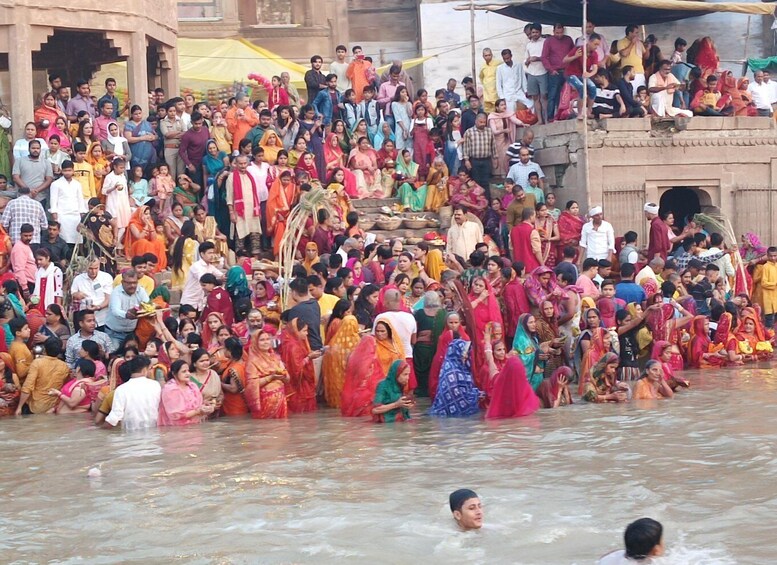 A large crowd gathered by a river, with people in colorful traditional attire. 4