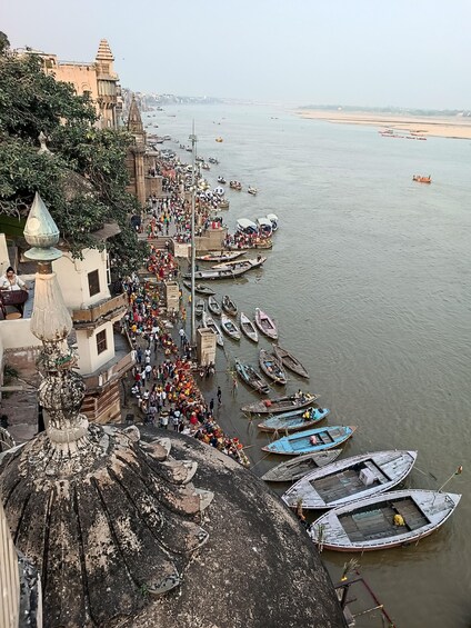 A riverside with boats docked and people walking along the shore. 2
