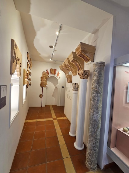 A museum corridor with ancient columns and wall art. 2