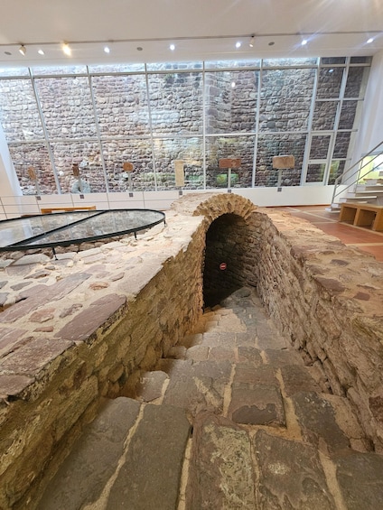 An indoor archaeological site with stone walls and a glass display case. 4