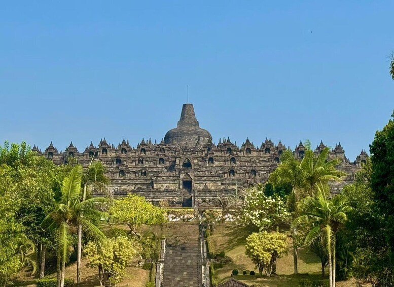 A large, ancient temple complex with multiple spires and a central dome, surrounded by lush greenery and palm trees. 4