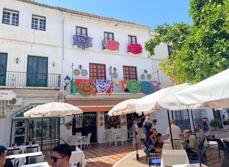 A courtyard with outdoor seating, a building with colorful decorations, and a sign for a bakery. 3