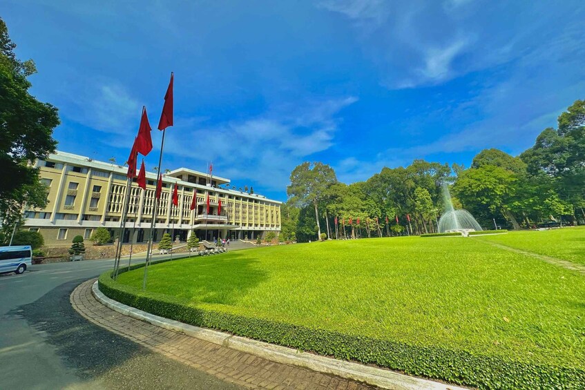 A building with red flags, a fountain, and a well-maintained lawn. 2