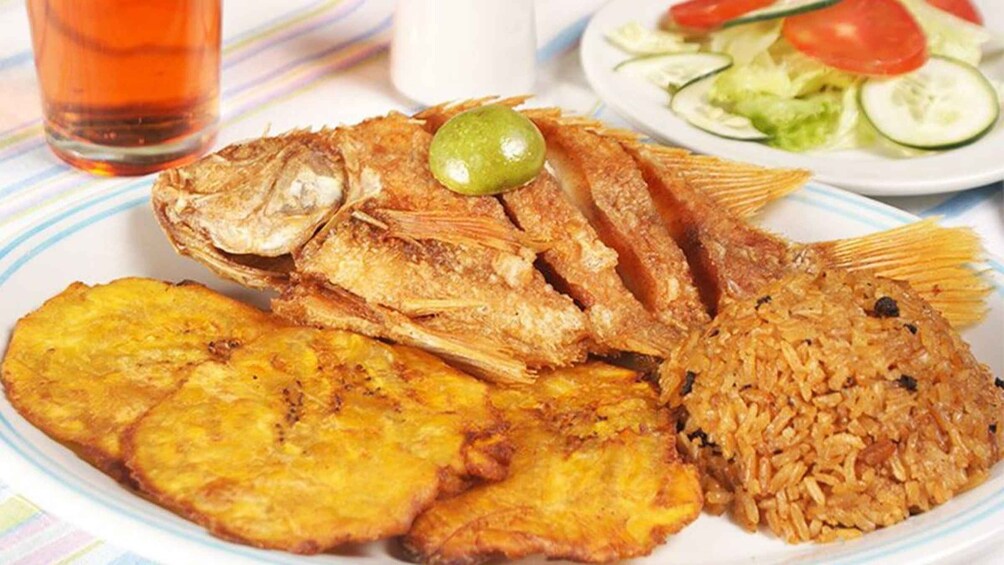 A plate with fried fish, fried plantains, rice, and a salad. 2