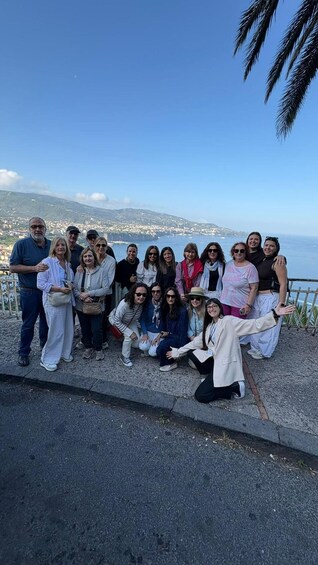 A group of people posing on a coastal overlook with a cityscape and ocean in the background. 1