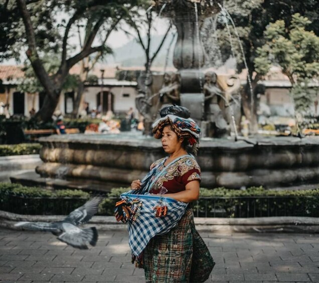 A person standing in a park with a fountain in the background. 5