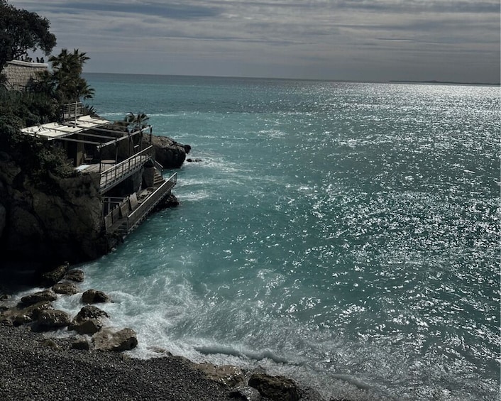 A rocky coastline with a pier extending into the sea, waves crashing against the rocks, and a clear sky. 2