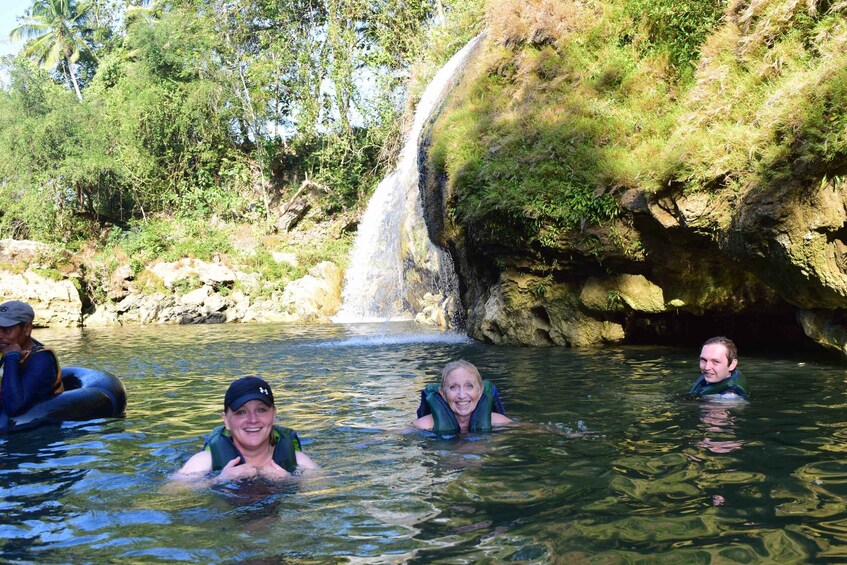 Eine Gruppe von Menschen in einer natürlichen Wasserlandschaft mit Wasserfall und felsigem Gelände. 5