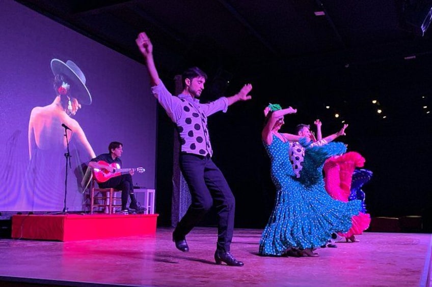 A stage performance with dancers and a guitarist. 3