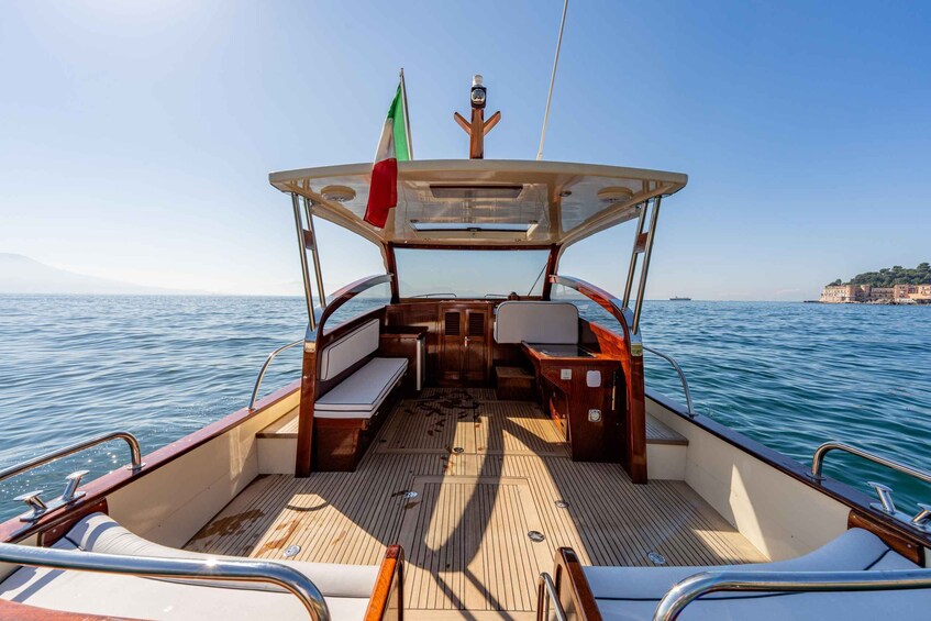 A boat deck with a flag, wooden flooring, and a view of the sea. 2