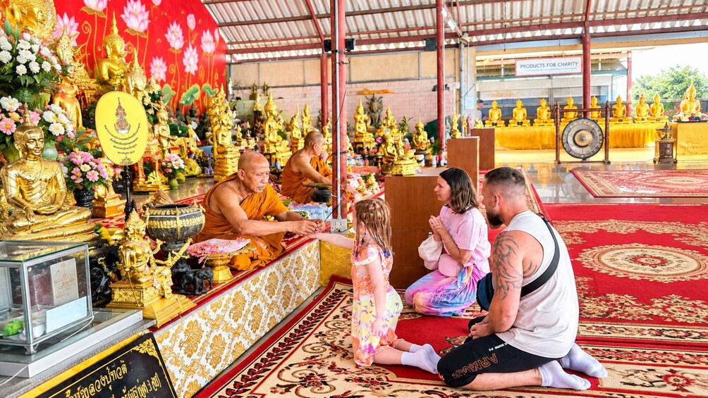 A temple interior with golden statues, a red carpet, and a sign for charity products. 5