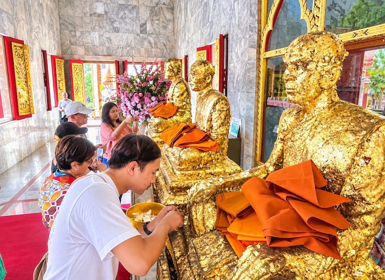 A golden statue in a temple with red and gold decorations, a red carpet, and people around. 5