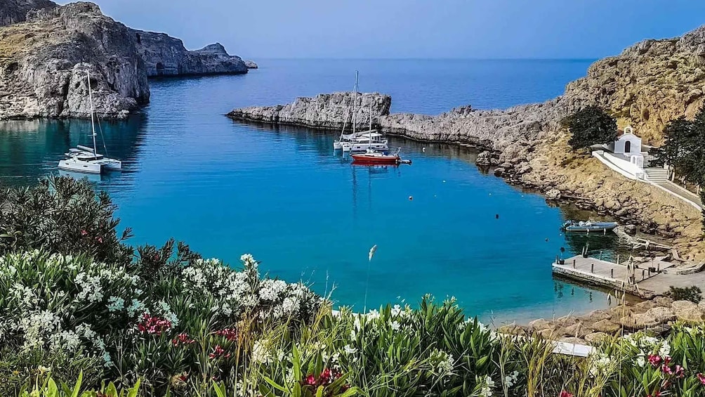 A coastal bay with boats, rocky cliffs, and a small white building. 1