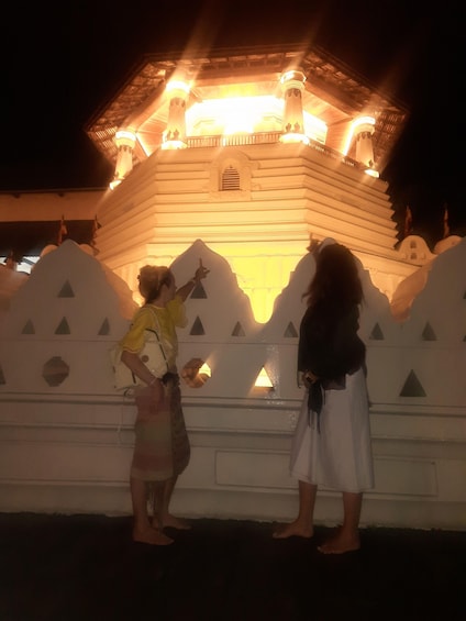 A group of people standing in front of a brightly lit building with a traditional architectural style. 3