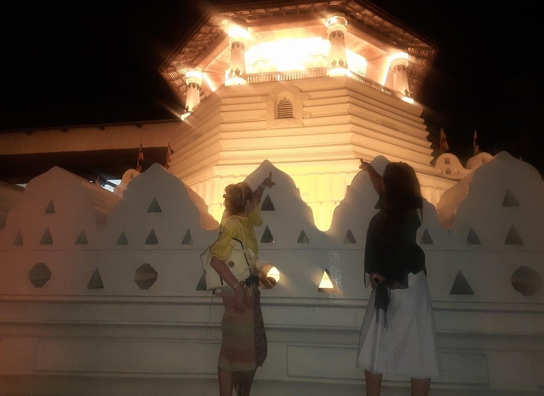 A night view of a traditional building with illuminated columns and a white facade with triangular patterns. 2