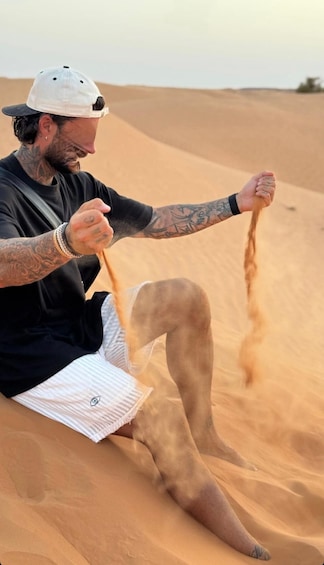 A person sitting on a sand dune, holding a rope. 1