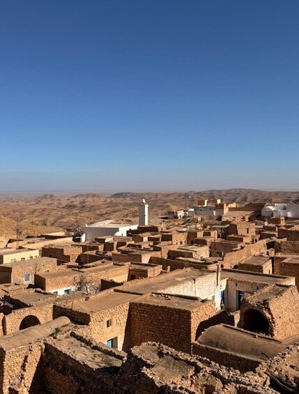 A desert town with traditional adobe buildings and a prominent minaret. 2