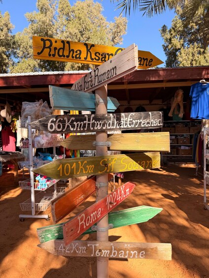 A wooden signpost with directional signs pointing to various destinations. 3