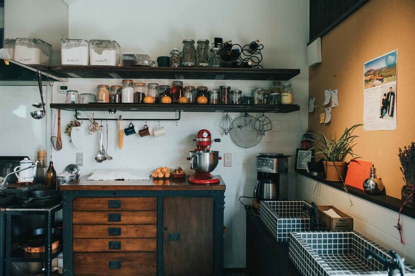 A kitchen with wooden cabinets, a red stand mixer, and various jars on shelves. 4