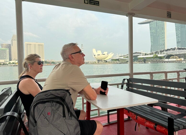 A couple sitting at a table with a cityscape and a lotus-shaped building in the background. 2