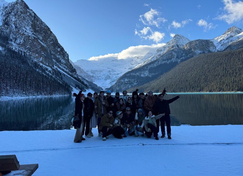 A group of people posing in a snowy landscape with a lake and mountains in the background. 2
