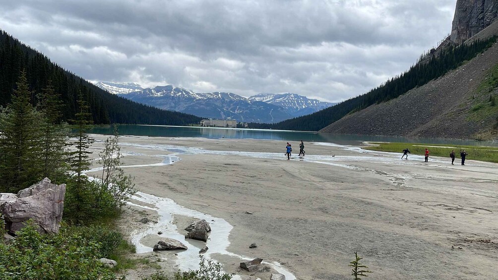 A riverbed with people walking, a lake, and mountains in the background. 3