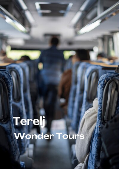 The interior of a bus with rows of seats and a person walking down the aisle. 2