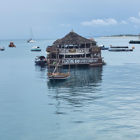 A floating bar and restaurant named 'Floating Beach Club' on calm waters with several boats around. 2