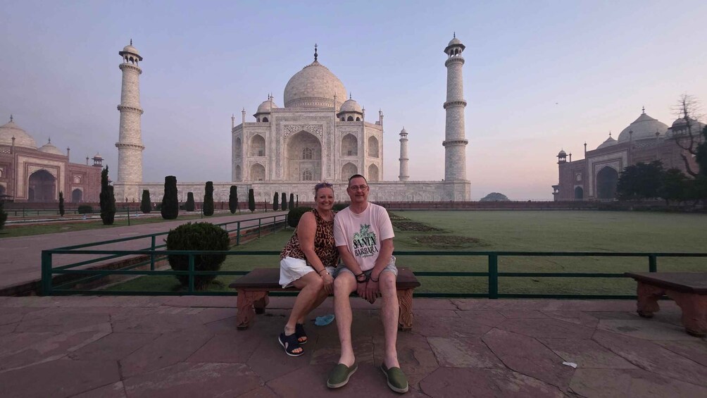 Two people sitting on a bench in front of the Taj Mahal. 5