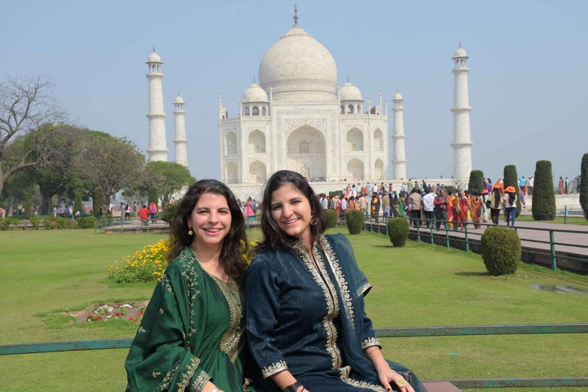 Two women sitting on a bench with the Taj Mahal in the background. 1