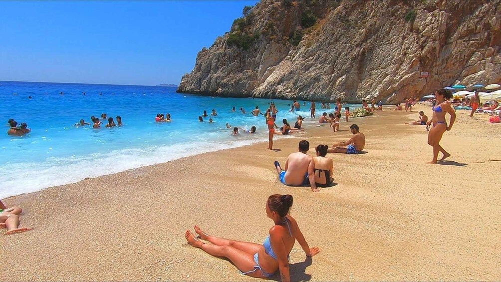 A crowded beach with people swimming and sunbathing. 3