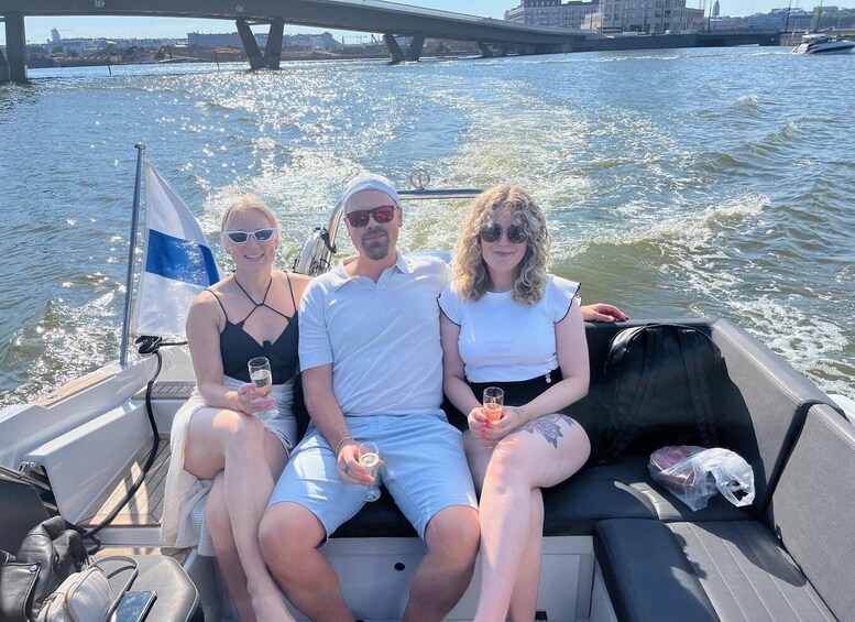 Three people on a boat with a flag, a bridge, and water in the background. 4
